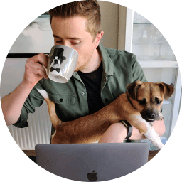 A picture of Clark Wickstone working while sipping coffee and holding his dog.